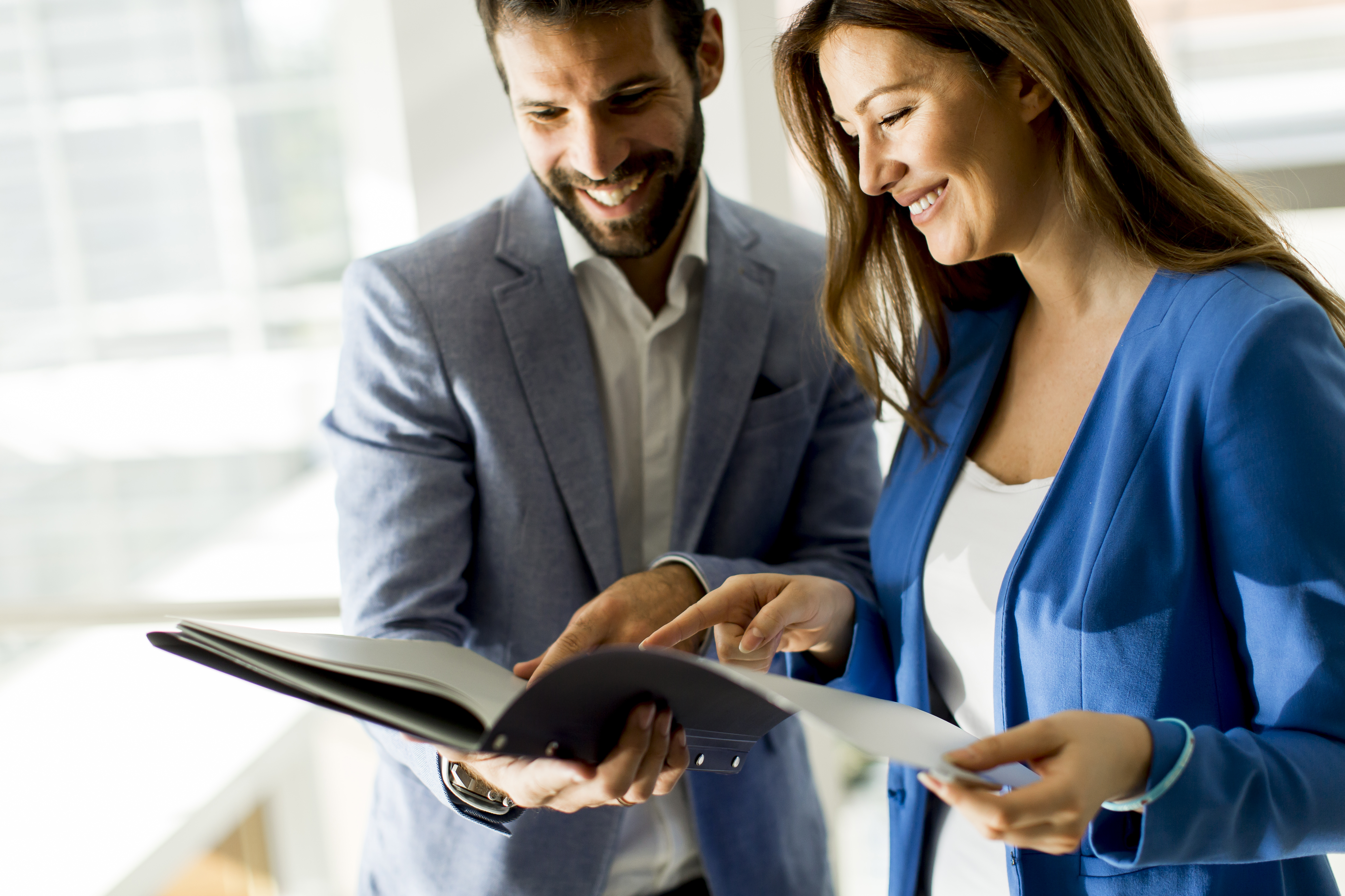 Kobieta i mężczyzna w średnim wieku stoją wspólnie i przeglądają razem dokumenty w biurze