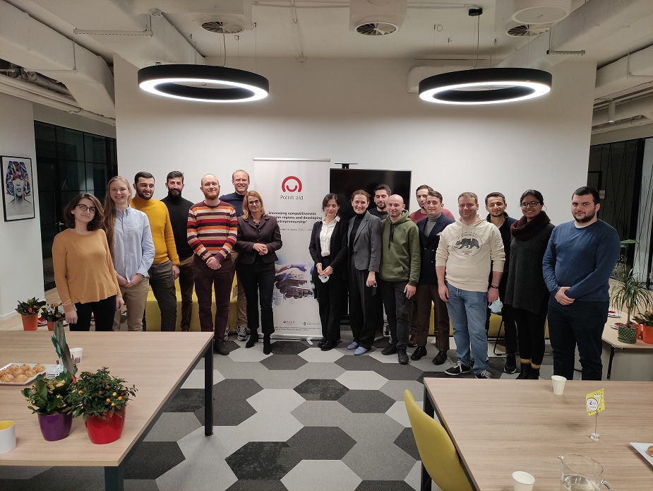 Grupa kobiet i mężczyzn w różnych wieku stoi na sali i pozuje wspólnie do zdjęcia