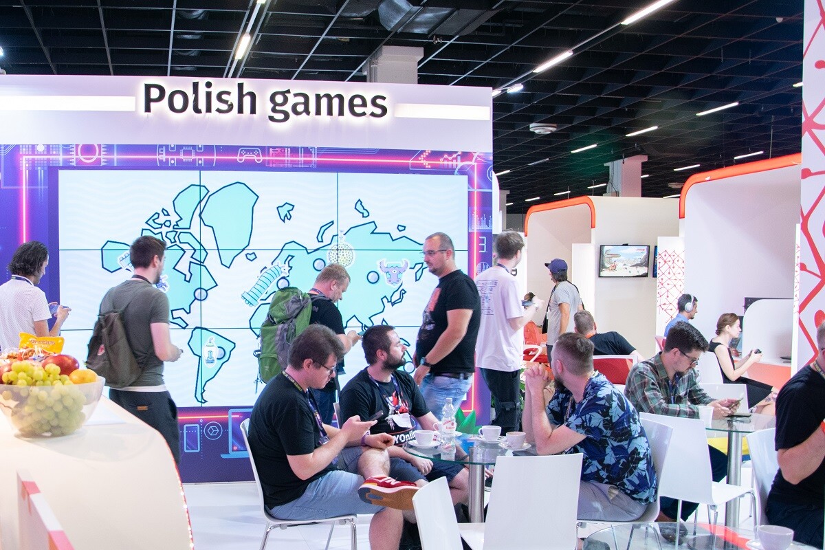 ludzie siedzą przy stolikach w hali targowo-wystawienniczej