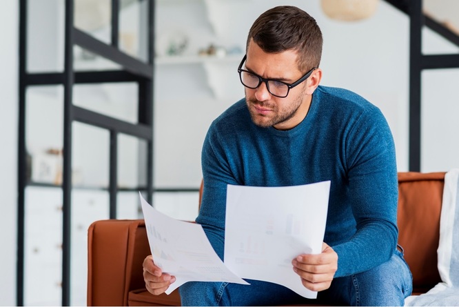 Mężczyzna siedzi i trzyma w ręku kartki