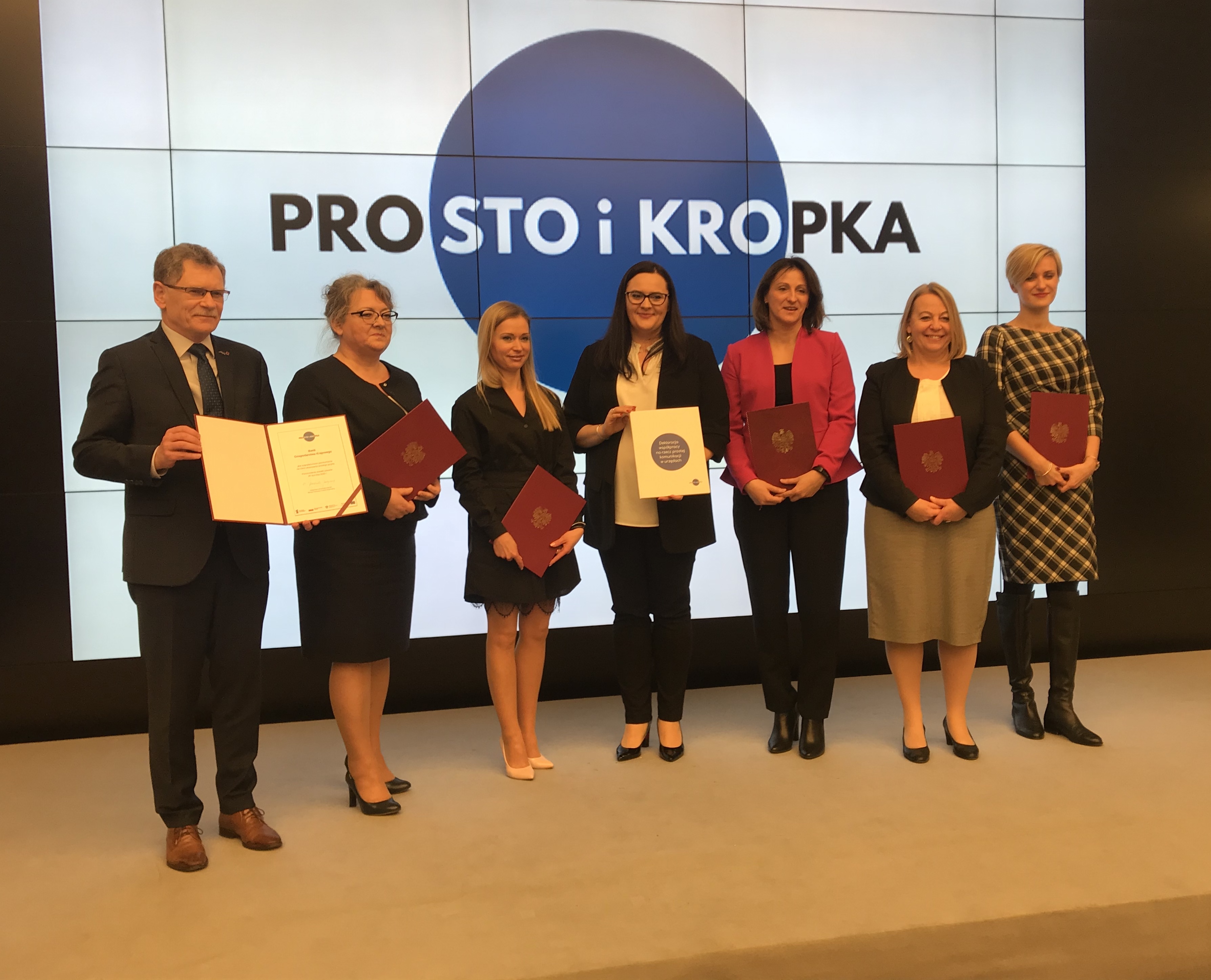 Sygnatariusze deklaracji współpracy na rzecz prostej komunikacji stojącyna scenie