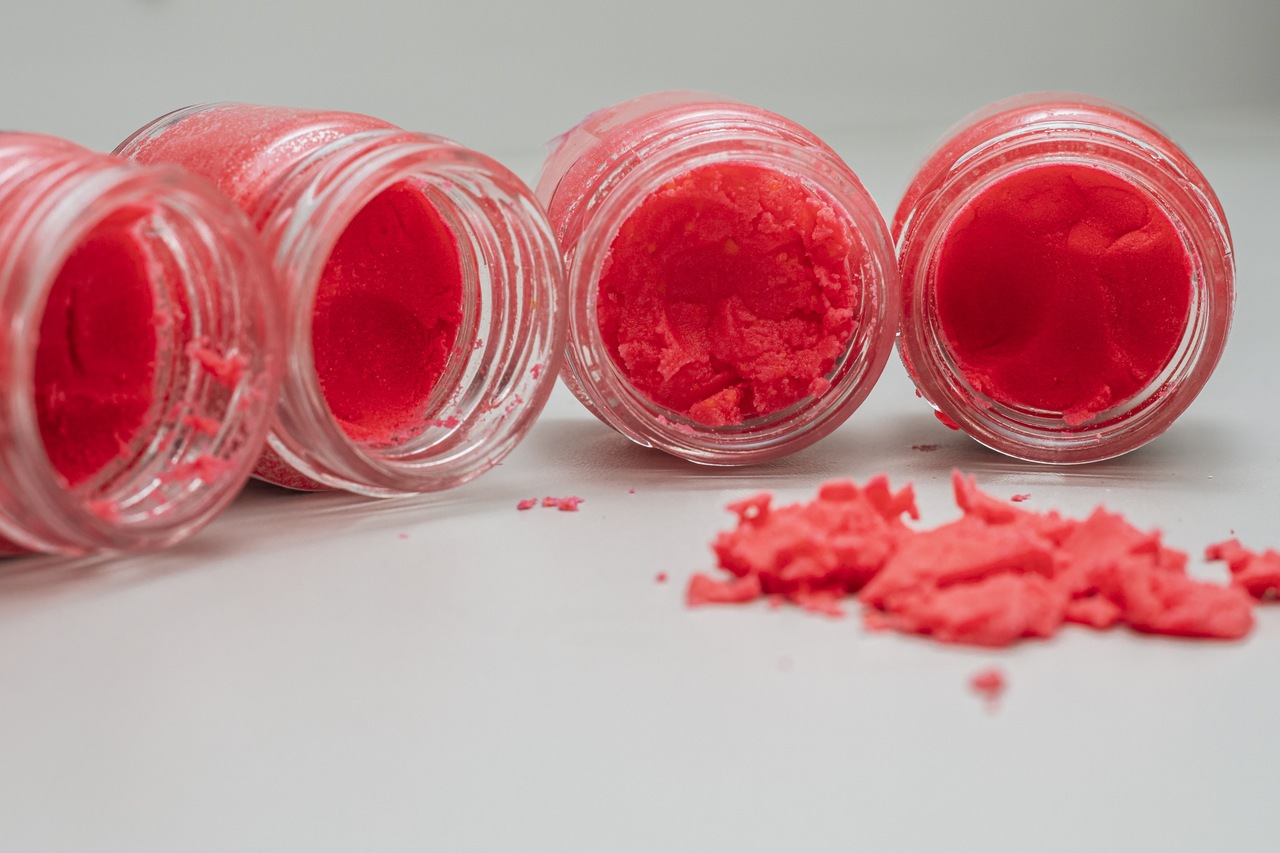 Otwarte małe słoiczki z czerwonym proszkiem, które leżą na stole