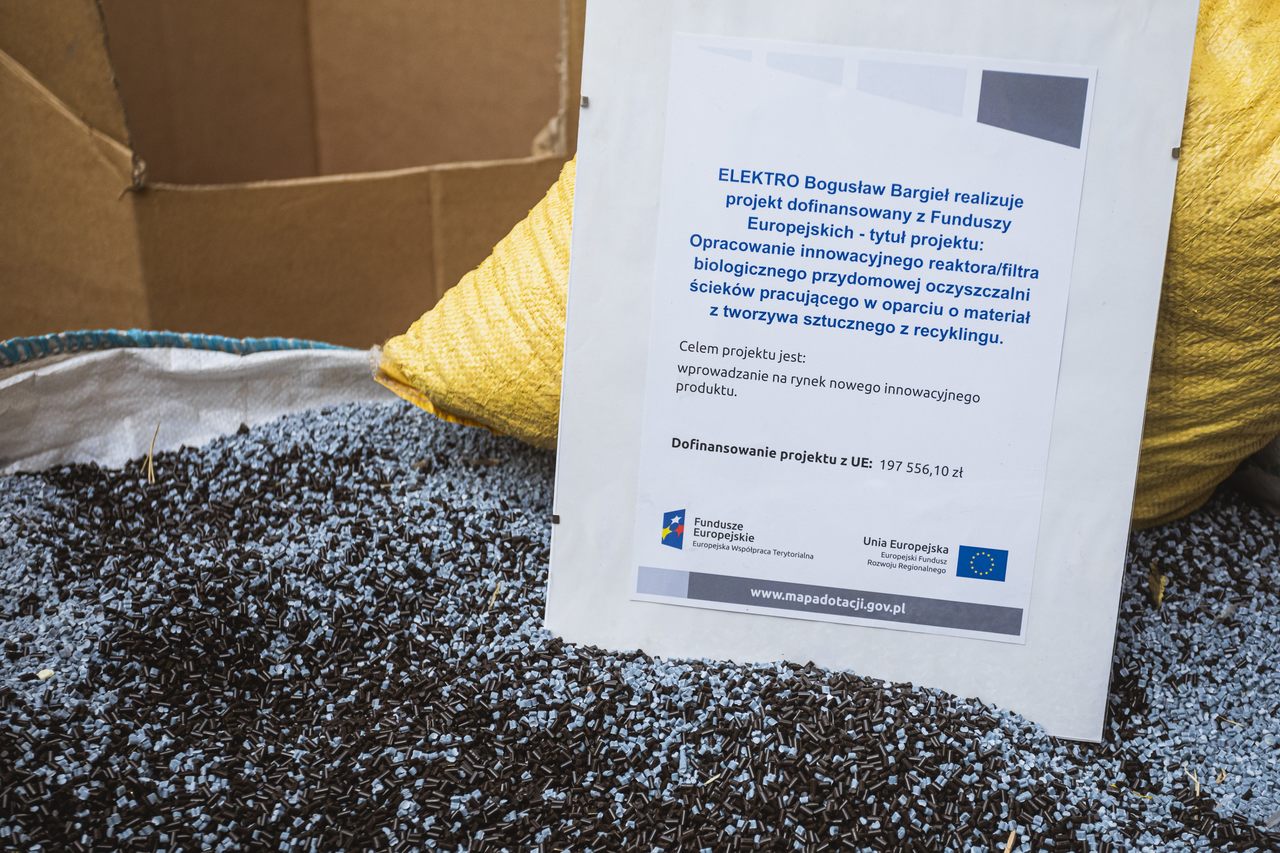 Czarne drobiny, przy nich postawiona kartka