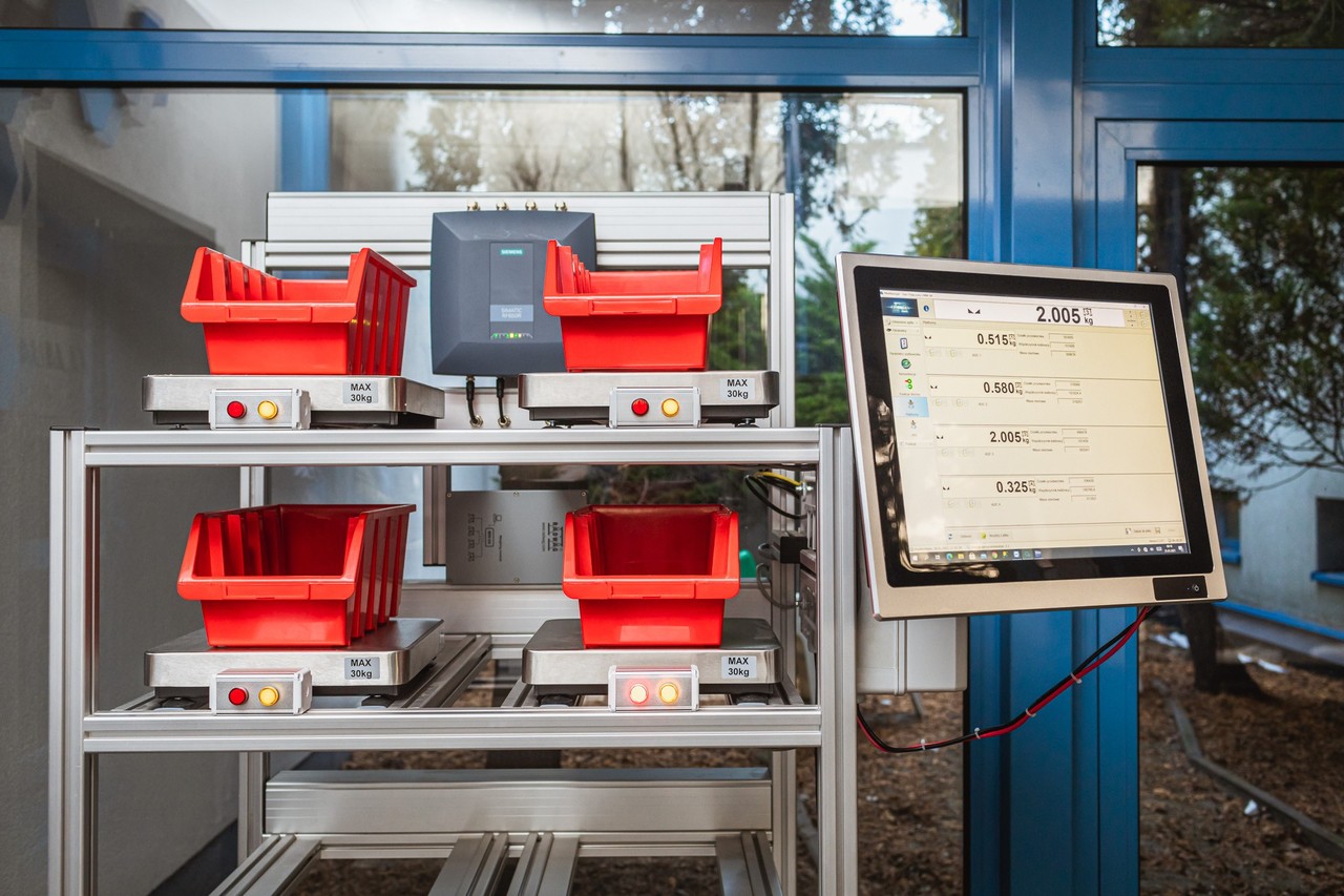 Pojemniki stojące na pólkach, przy nich monitor