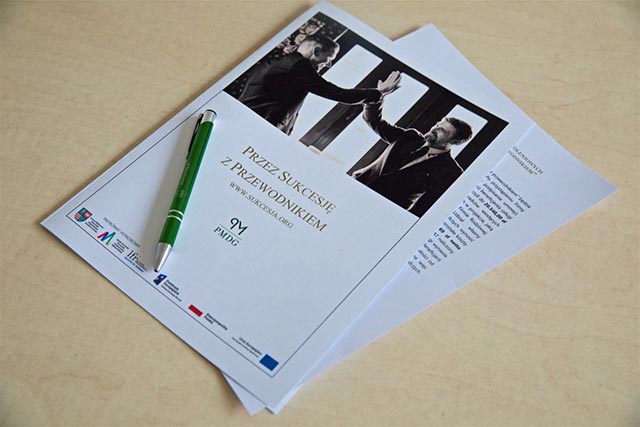 Widok biurka, stołu, na którym połozona jest kartka z napisem "Przez sukcesję z przewodnikiem"