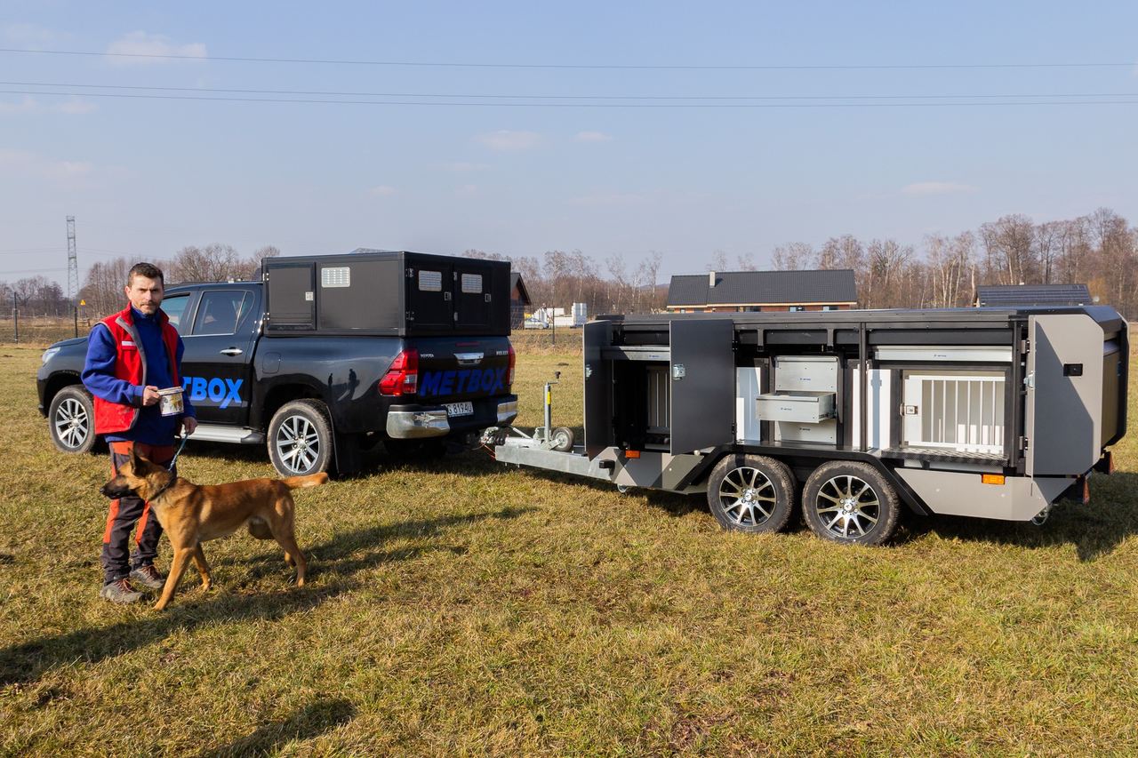 Przyczepa połączona z samocodem i mężczyzna z psem obok