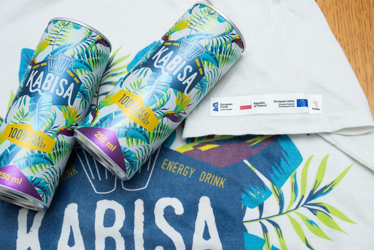 Dwie puszki leżą na koszulce z logiem firmy